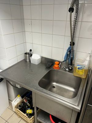 un évier dans une petite cuisine où le plan de travail est encombré