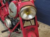 a red motorcycle parked in a garage with a blue wall
