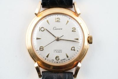 une montre-bracelet en or avec un cadran blanc sur un bracelet noir