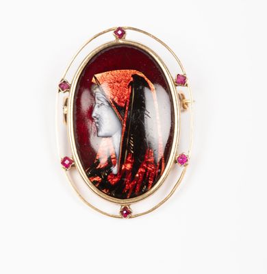 une photo représentant une broche à l'effigie d'une femme portant un chapeau rouge
