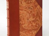 an old book with a red cover and a brown leather cover