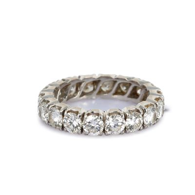 un gros plan d'une bague « éternité » sertie de diamants sur fond blanc