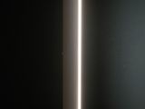 a white lamp sitting on top of a wooden floor next to a black wall
