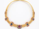 un collier en or orné de pierres bleues et roses sur fond blanc