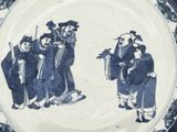 a blue and white plate with a picture of a group of people on it