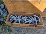 a wooden box filled with metal pipe fittings on the ground