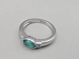 a close up of a ring with a green stone on it
