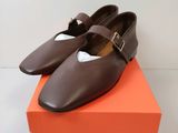 des chaussures en cuir marron avec des boucles, posées sur une boîte orange