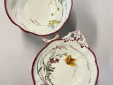 two bowls with floral designs on them sitting on a white surface