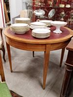 Table ronde en merisier ; plateau recouvert d'un cuir.
