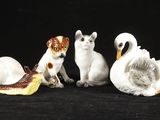 cinq figurines représentant des chats et des cygnes sur fond noir