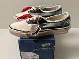 une paire de baskets sans lacets « Vans » dans une boîte posée sur une table