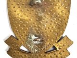 an image of a gold metal plaque with a face on it