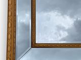 an image of a gold framed mirror with a cloudy sky in the background