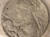 une image représentant un médaillon en pierre orné du visage d'une femme