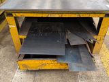 a yellow table with metal sheets stacked on top of it