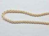a close up of a pearl necklace on a white surface