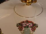 a white plate with a gold handle and a bowl with a flower design on it