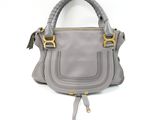 a gray handbag with a gold handle on a white background