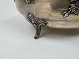 a silver bowl with a handle on a white table