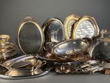 a lot of silver plates and silver dishes on the table