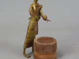 bronze figurine of a woman holding a bird next to a pot