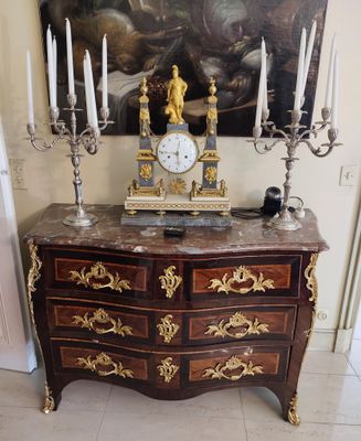 a clock on top of a chest of drawers in a room