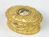 a small gold box with a picture of a woman on it