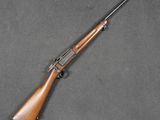 a rifle with a wooden barrel and a wooden handle on a gray surface