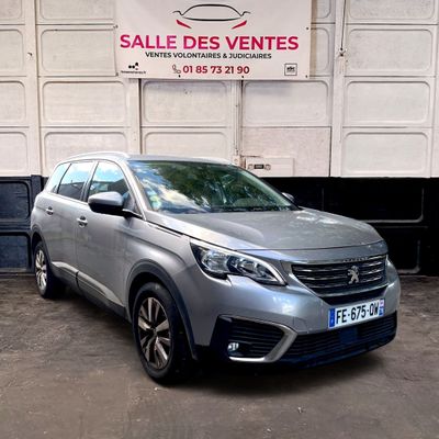 La voiture argentée est garée devant un immeuble surmonté d'une enseigne.