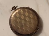 a gold pocket watch sitting on a marble surface