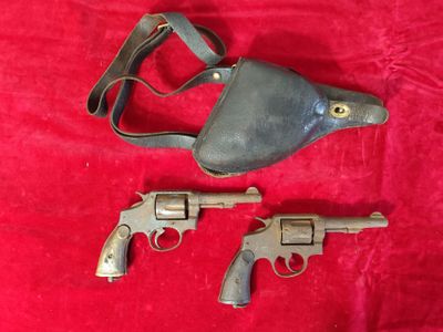deux revolvers et un étui sur un tissu rouge