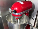 a red stand mixer with a metal bowl and a wooden skewer