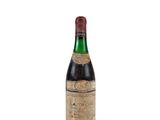 une vieille bouteille de vin posée sur une surface blanche