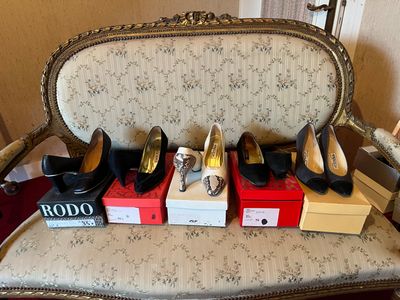 several pairs of women ' s shoes sitting on top of boxes on a chair