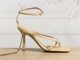 gold strappy heels with ankle chain on a wooden table