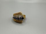 gros plan d'une bague en or avec des pierres bleues et blanches
