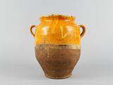 un vase orange et marron posé sur une table blanche