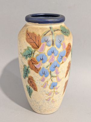 un vase jaune orné de fleurs et de feuilles bleues