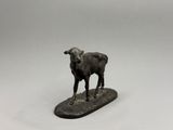 figurine représentant un mouton debout sur une planche en bois