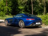a blue sports car driving down the road in the woods