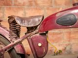 an old red motorcycle with a saddle on it ' s back