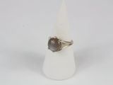 bague en argent ornée d'une pierre brune posée sur un cône blanc