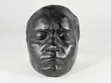 une sculpture noire représentant la tête d'un homme aux yeux fermés