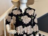 Le mannequin porte une chemise à fleurs noire et blanche et un chapeau.