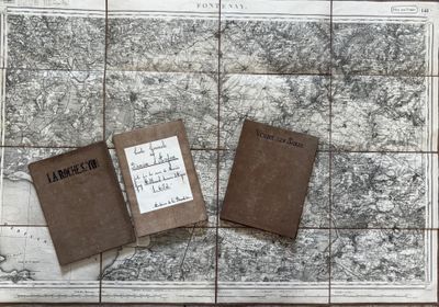 deux vieux livres posés sur une carte, elle-même posée sur une table