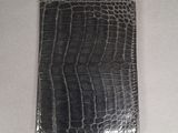 a black alligator skin wallet sitting on top of a white table