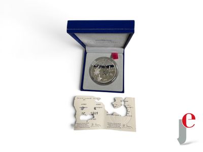 une pièce d'argent dans une boîte bleue entourée d'un ruban rouge