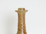 a brown vase sitting on a table with a white wall in the background