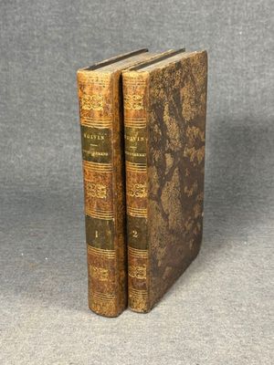 two old books sitting on top of each other on a table